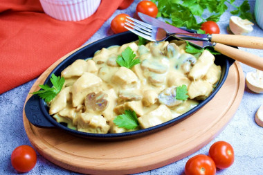Chicken fillet with mushrooms in a frying pan in sour cream