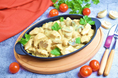 Chicken fillet with mushrooms in a frying pan in sour cream