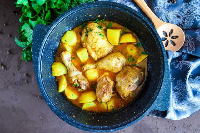 Stewed chicken with potatoes in a cauldron on the stove