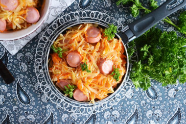 Stewed cabbage with sausages in a frying pan