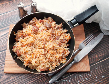 Rice with stewed meat in a frying pan