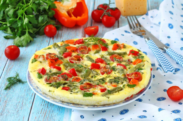 Omelet with vegetables, cheese and herbs in a frying pan