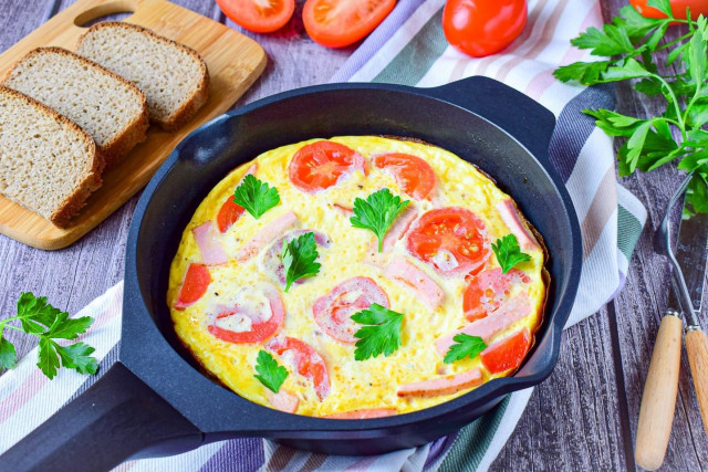 Omelet in a frying pan with sausage and cheese