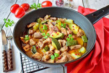 Pork with zucchini stewed in a frying pan