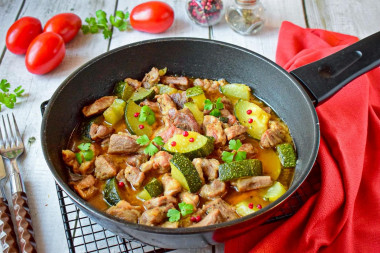 Pork with zucchini stewed in a frying pan