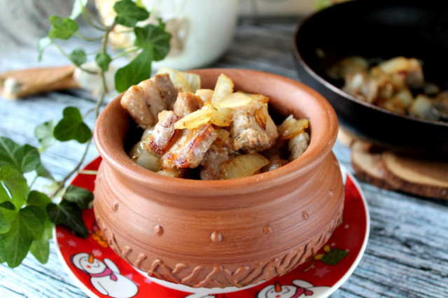 Pork meat in pieces in a frying pan with onions