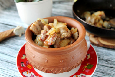 Pork meat in pieces in a frying pan with onions