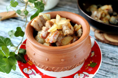 Pork meat in pieces in a frying pan with onions