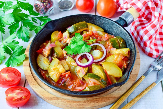 Stewed zucchini with tomatoes and garlic in a frying pan