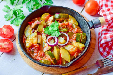 Stewed zucchini with tomatoes and garlic in a frying pan