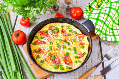 Omelet with tomatoes and cheese in a frying pan