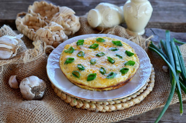 Omelet with green onions in a frying pan