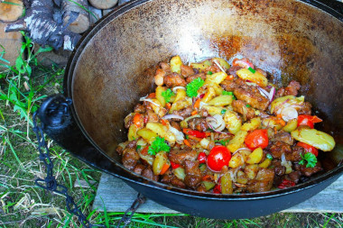 Potatoes with meat on a fire in a cauldron