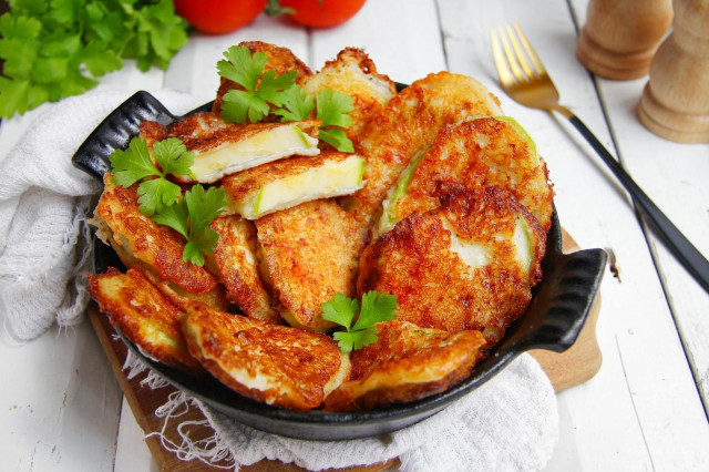 Zucchini in batter with cheese in a frying pan