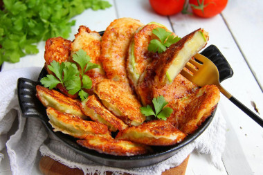 Zucchini in batter with cheese in a frying pan