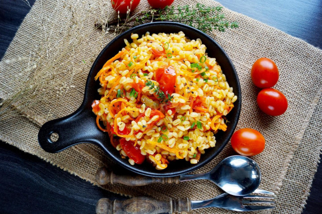 Bulgur with onions and carrots in a frying pan