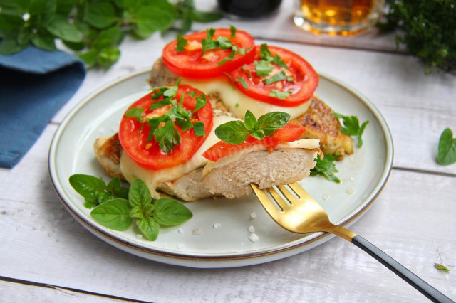 Chicken fillet with tomatoes and cheese in a frying pan