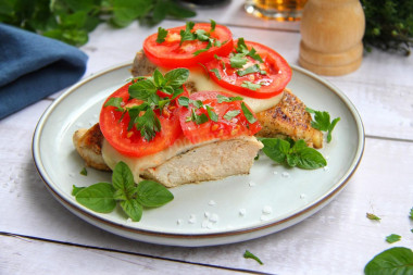 Chicken fillet with tomatoes and cheese in a frying pan