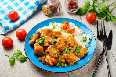 Pork with mushrooms in a frying pan in sauce with onions