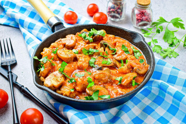 Pork with mushrooms in a frying pan in sauce with onions