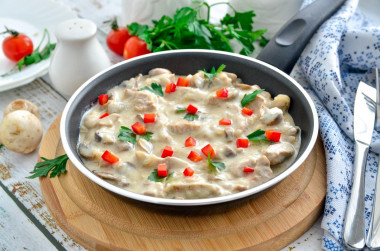 Meat with mushrooms in sour cream sauce in a frying pan