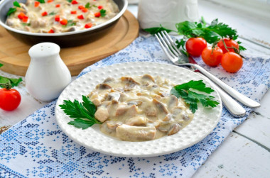 Meat with mushrooms in sour cream sauce in a frying pan