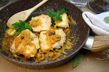 Cod stewed with onions and carrots in a frying pan