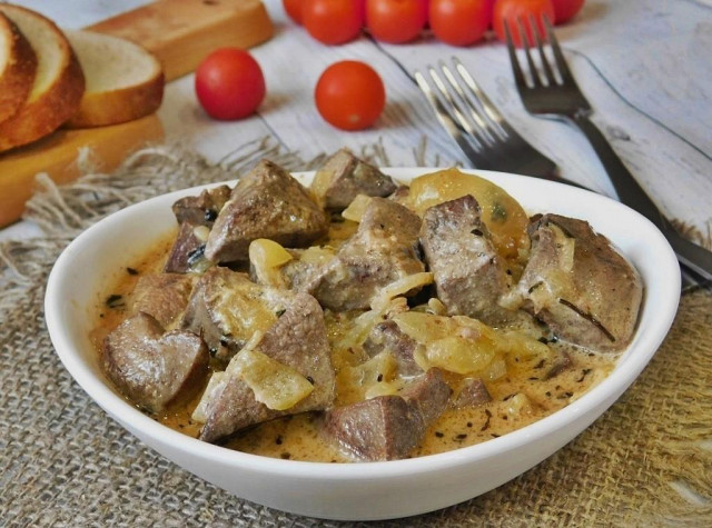 Pork liver in sour cream with onions in a frying pan