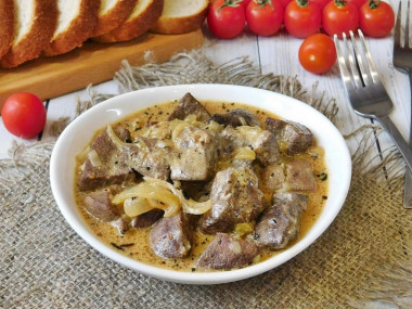 Pork liver in sour cream with onions in a frying pan