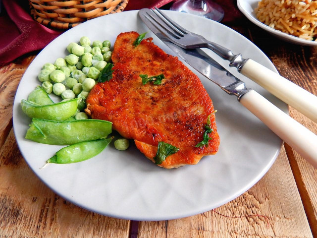 Pork steak in a frying pan with black pepper