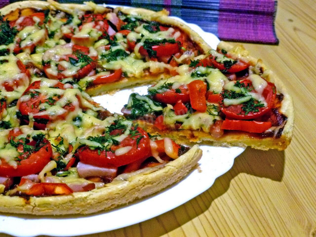 Pizza on liquid dough with pork, tomatoes and peppers