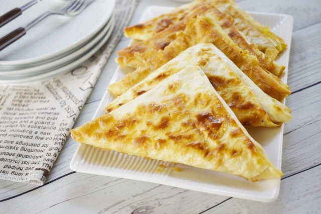 Triangles of pita bread with egg and cheese in a frying pan