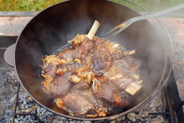 Beef ribs in a cauldron with onions