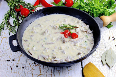 Chicken hearts in sour cream sauce in a frying pan