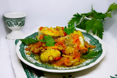 Stewed hake with onions, carrots and vegetables in a frying pan