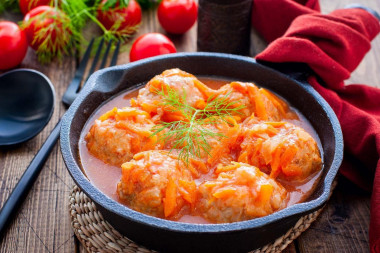 Meatballs in tomato paste with rice in a frying pan