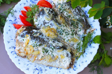 Fried crucian carp in sour cream in a frying pan