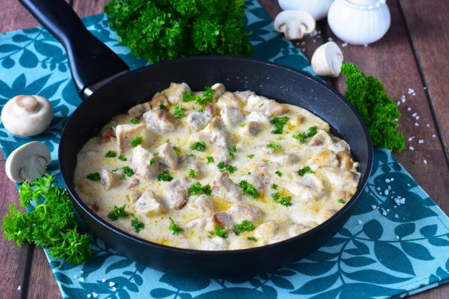 Pork in sour cream sauce with mushrooms in a frying pan