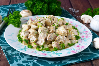 Pork in sour cream sauce with mushrooms in a frying pan