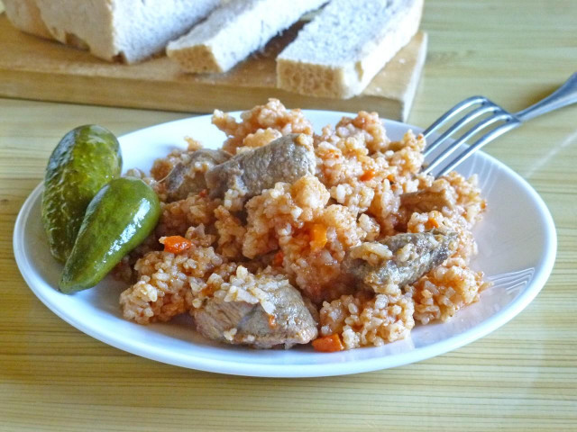 Pilaf with tomato paste and pork in a saucepan on the stove