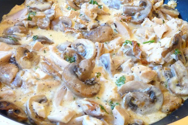 Chicken with mushrooms in sour cream in a frying pan