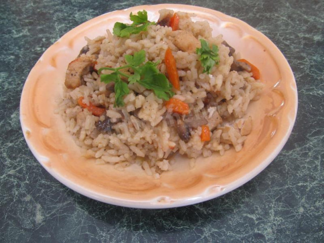 Pilaf with mushrooms and chicken on the stove