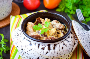 Pork meat in pots in the oven with mushrooms and cheese