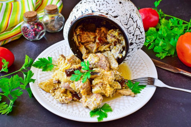 Pork meat in pots in the oven with mushrooms and cheese