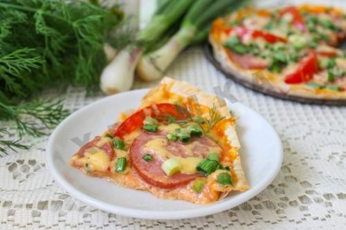 Pizza on thin pita bread baked with smoked sausage