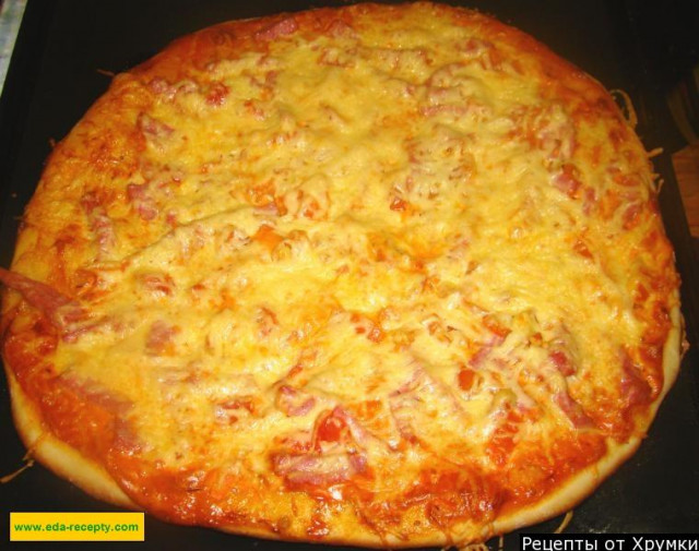 Yeast dough pizza with sausage and tomatoes filling