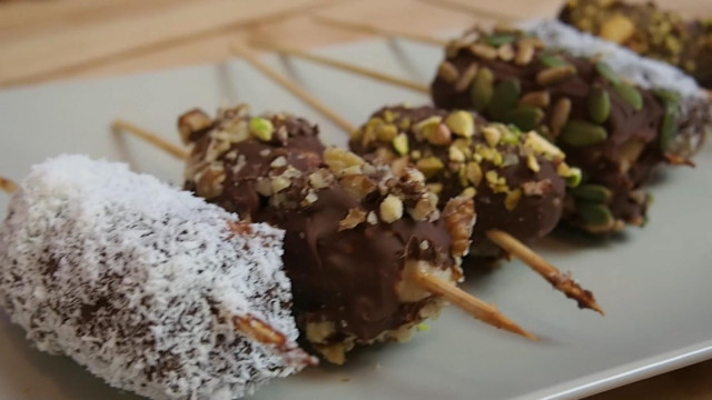 Chocolate-covered bananas sprinkled with nuts and coconut shavings