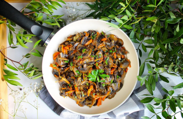 Fried mushrooms with onions and carrots in a frying pan