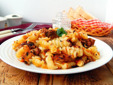 Chicken hearts with pasta on frying pan