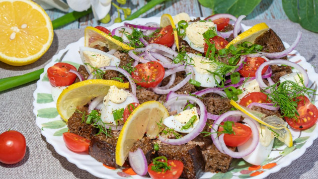 Cod liver salad with crackers and tomatoes with onions